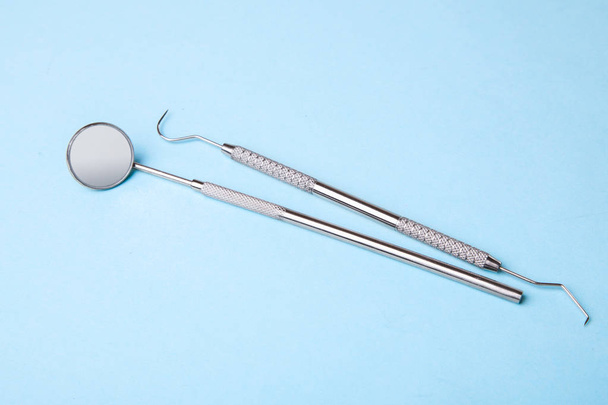 Instruments dentaires. Miroir dentaire et crochet de sonde sur bleu
 - Photo, image
