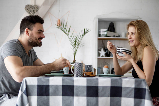 Loving couple sitting at a kitchen table, having a breakfast together - Фото, изображение