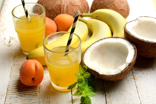 tropical fruits drink with around coconut, bananas and apricots - closeup - Φωτογραφία, εικόνα