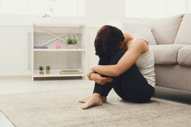 Расстроенная девушка сидит на полу
 - Фото, изображение