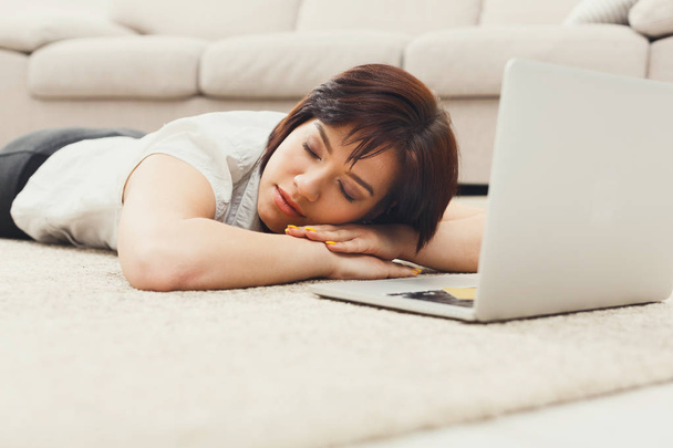 Γυναίκα στον ύπνο, ξαπλωμένο στο πάτωμα κοντά στο φορητό υπολογιστή - Φωτογραφία, εικόνα