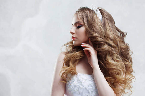 Young charming bride in wedding dress. Make-up and hairstyle with voluminous curls - Foto, afbeelding