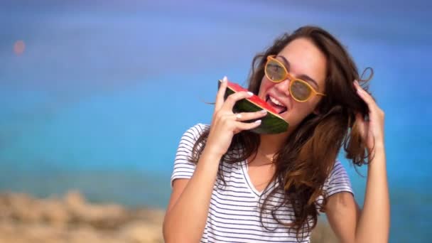 スローモーションでビーチでスイカを食べて笑顔の女性。女性の感情 - 映像、動画