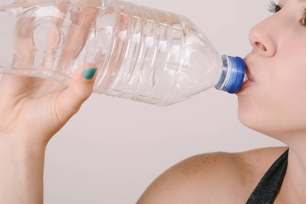 Close up view of sporty woman drinking water. Sport concept. Indoors - Fotografie, Obrázek