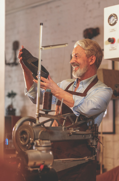 Gelukkig bejaarde man in uniform in een workshop - Foto, afbeelding