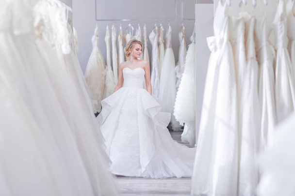 Beautiful woman in a white dress in wedding shop - Fotó, kép