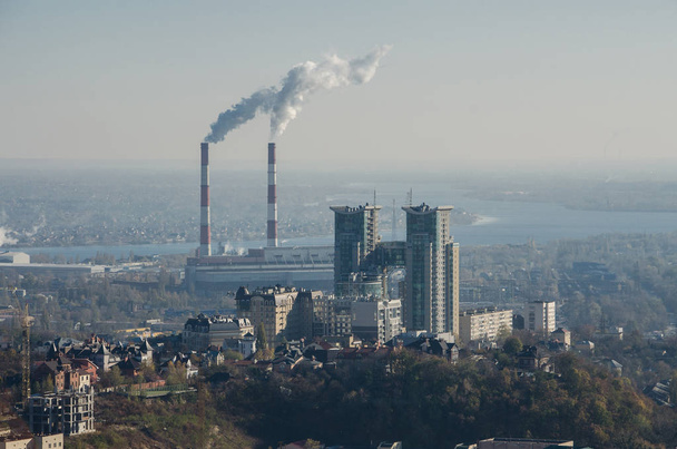 Загрязнение воздуха дымом, исходящим из двух труб завода. Промышленная зона в городе. Киев, Украина, вид с воздуха
 - Фото, изображение
