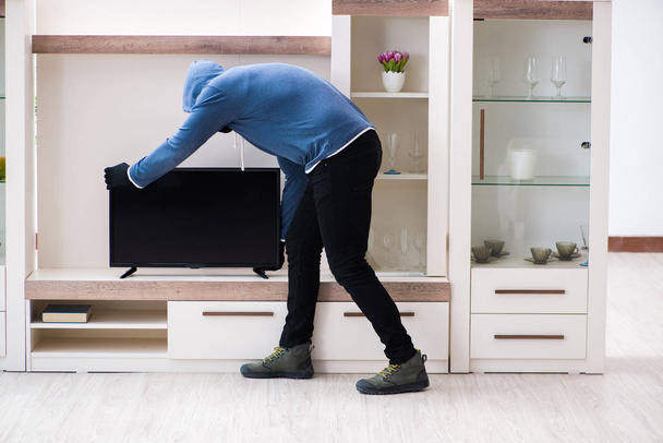 Man burglar stealing tv set from house - Foto, immagini