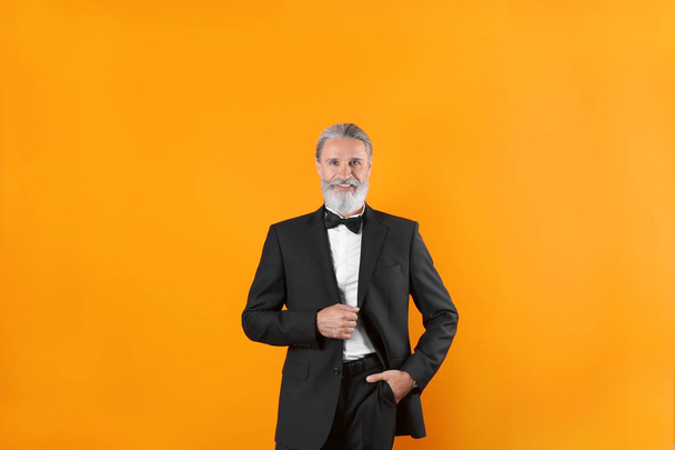 Handsome bearded mature man in suit on color background - Фото, изображение