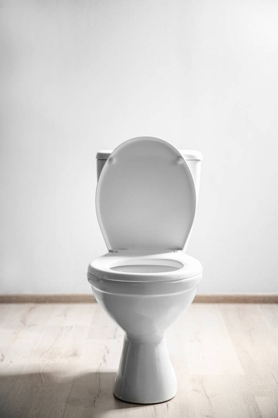 New ceramic toilet bowl near light wall - 写真・画像
