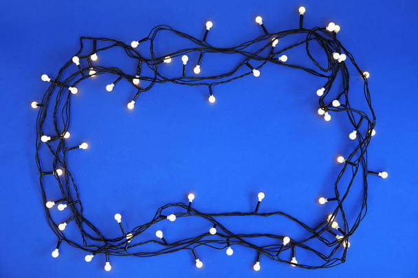 Glowing Christmas lights on color background, top view - Foto, Imagem