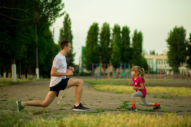 Urheilullinen nuori isä ja pieni tytär harjoittelevat stadionilla. Terveellinen elämäntapa
 - Valokuva, kuva