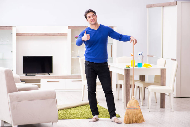 Młody człowiek sprzątanie podłogi miotłą - Zdjęcie, obraz