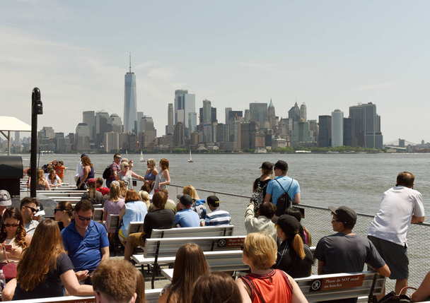 New York, USA - June 09, 2018: Passengers of the Statue of Liberty Ferry and  buildings of financial district in lower Manhattan at the background. - Photo, image