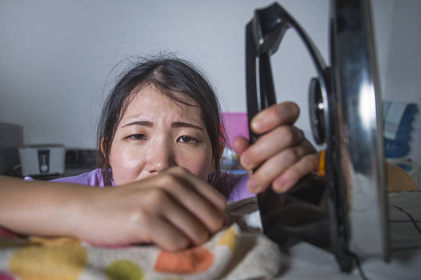 jonge mooie gefrustreerd en gestresst Aziatische Chinese vrouw met ijzer keuken strijken kleding wanhopig en overweldigd in huis meid service huishoudelijk werk huishoudelijke stress thuis te werken - Foto, afbeelding