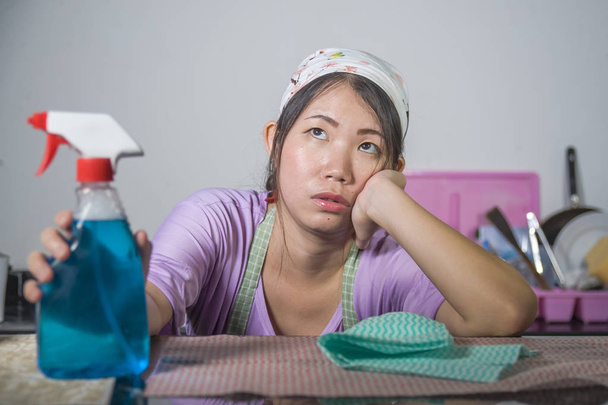 young pretty overworked and stressed Asian Korean service maid woman working domestic cleaning and washing with spray bottle angry and upset in housework and housekeeping stress - Zdjęcie, obraz