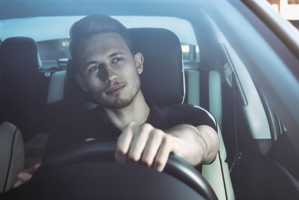 Pohledný muž sedí v autě a držení volantu. - Fotografie, Obrázek