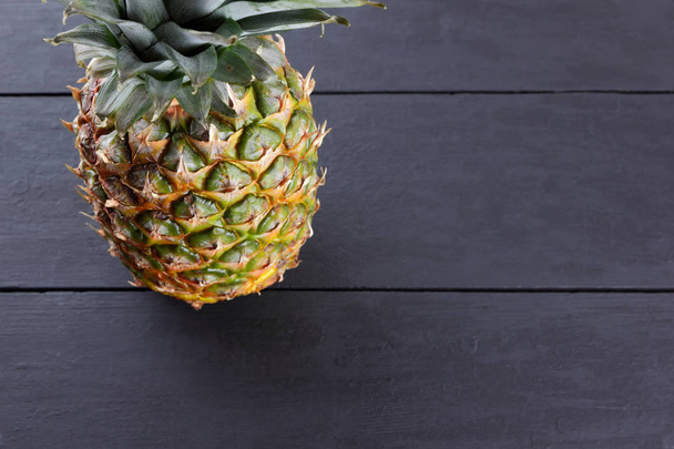 Pineapple on wooden boards, pineapple with leaves on black background, tropical fruit with copy space, blank for designer, vegetarian food, fruit for salad preparation, top view - Valokuva, kuva