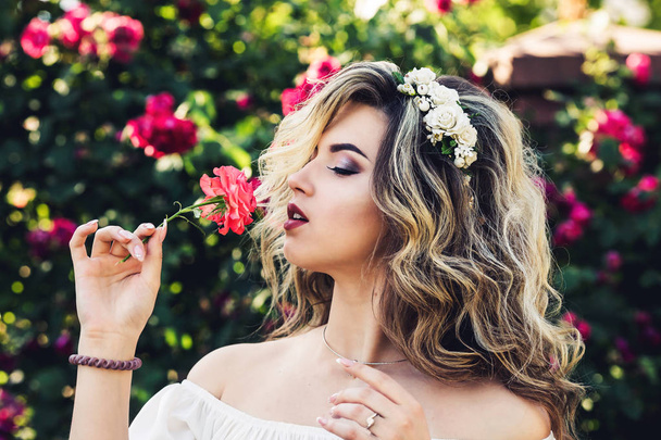 Retrato ao ar livre de jovem bela menina encaracolada perto forjada treliça com rosas
. - Foto, Imagem