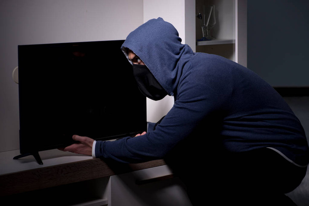 Бурґларський злодій краде телевізор з багатоквартирного будинку
 - Фото, зображення