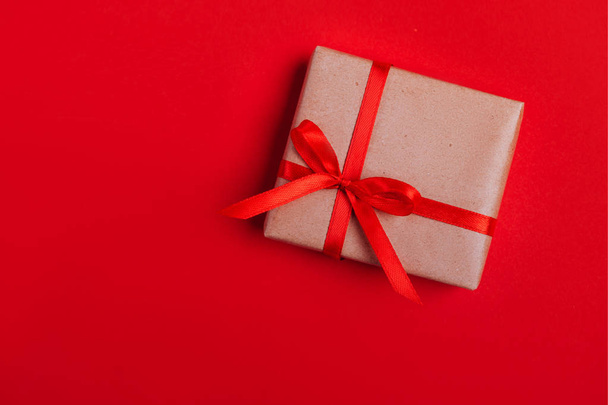 Present box with red bow on colorful background. Flat lay style. - Photo, Image