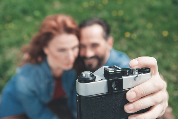 Joyful man and woman taking photos on grassland  - Foto, Imagem
