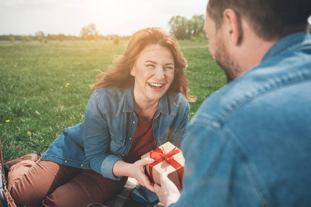 Cheerful lady receiving present box from husband in the nature  - Photo, image