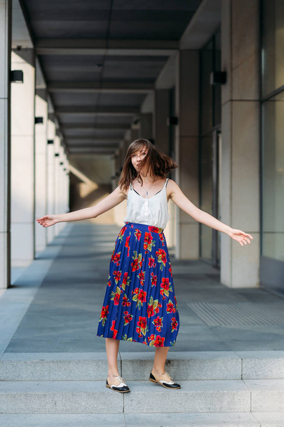Stylish woman dancing in the street.Woman portrait indoors. Fashion lifestyle portrait of pretty woman. Woman portrait outdoors in floral skirt and white top.  - Fotoğraf, Görsel