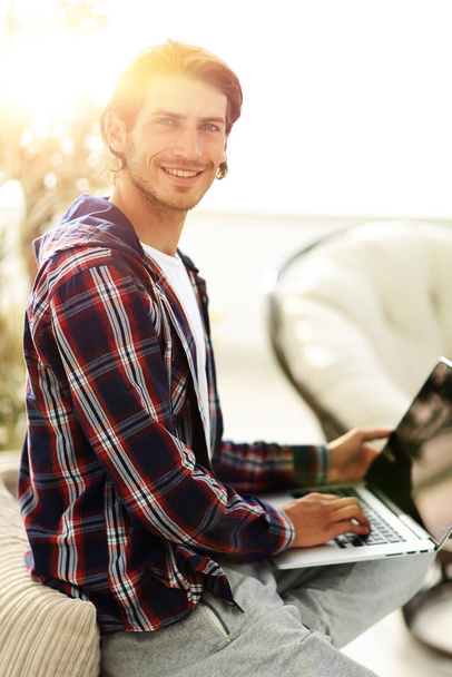 stylish young man working on laptop and looking at camera - Foto, imagen