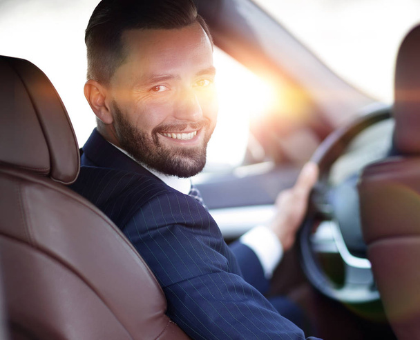 businessman sitting at the wheel of a car and looking at the camera - Foto, Bild