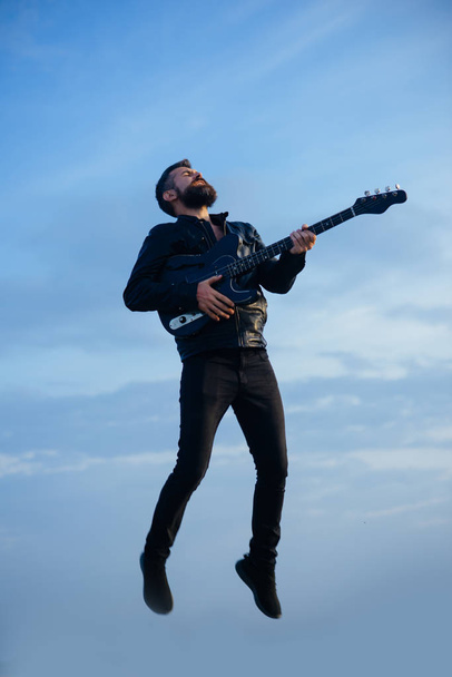 Music and freedom make him happy. Music, bearded hipster play guitar flying in blue sky - Φωτογραφία, εικόνα