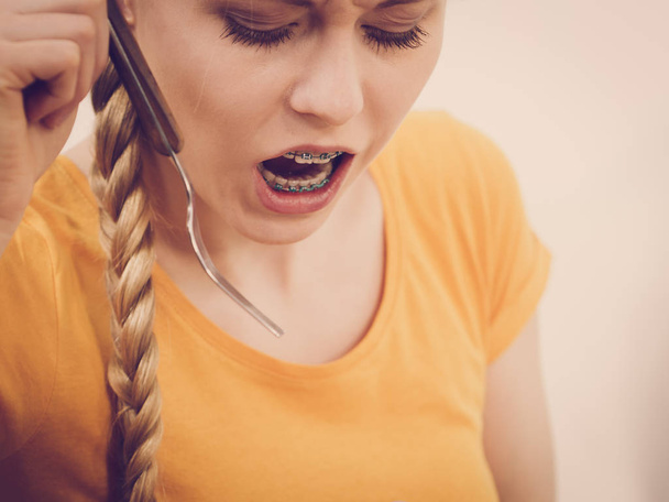 Mujer conmocionada con la boca abierta ancha sosteniendo tenedor siendo muy sorprendido. Primer plano retrato
 - Foto, imagen