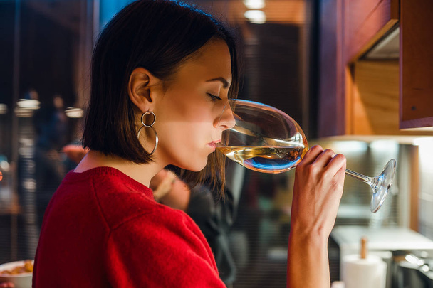Giovane donna bruna che beve vino bianco
 - Foto, immagini
