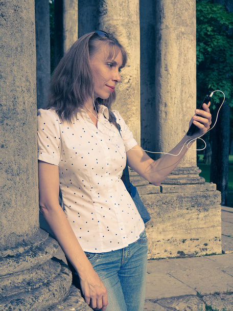 Telefon ile headhpones açık havada kullanan sarışın kız portresi. - Fotoğraf, Görsel