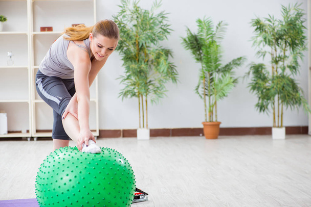 Νεαρή γυναίκα άσκηση με μπάλα σταθερότητας στο γυμναστήριο - Φωτογραφία, εικόνα