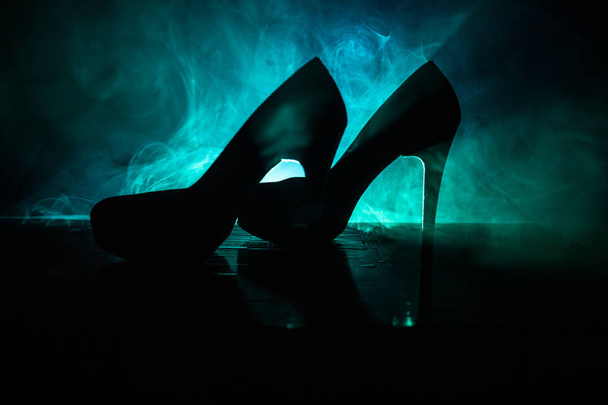 Black suede high heel women shoes on dark toned foggy background. Close up. Women power or women domination concept. Selective focus - 写真・画像