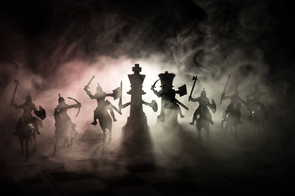 Medieval battle scene with cavalry and infantry on chessboard. Chess board game concept of business ideas and competition and strategy ideas Chess figures on a dark background with smoke and fog. - Photo, Image