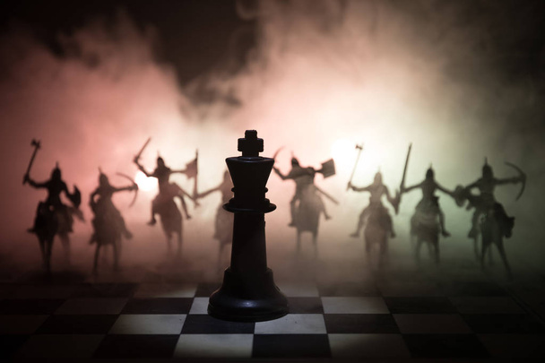 Středověká bitva scény s jezdectva a pěchoty na šachovnici. Koncept desková hra šachy podnikatelských nápadů a myšlenek konkurence a strategii šachové figurky na tmavém pozadí se kouře a mlhy. - Fotografie, Obrázek