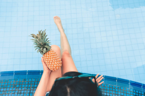  Ritratto di giovane donna che si rilassa in piscina con ananas., Summer holiday fashion concept
. - Foto, immagini