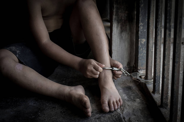 das Kind wird in einem eisernen Käfig gefangen und mit einer Fußfessel gefesselt, Opfer von Menschenhandel, Gewalt gegen Kinder, internationaler Tag gegen den Menschenhandel - Foto, Bild