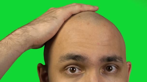 Homem careca com metade da cara tocando a cabeça no fundo verde
 - Filmagem, Vídeo