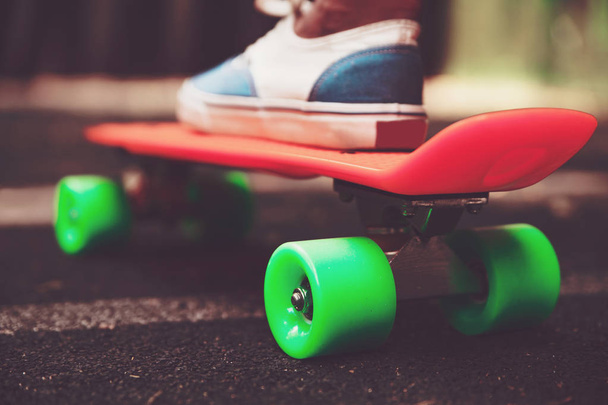 Close up of feet of girl sneakers rides on orange penny skateboard on asphalt - Φωτογραφία, εικόνα
