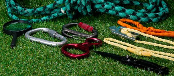 items for extreme sports and tourism are on the green lawn, ropes, carabiners. - Фото, зображення