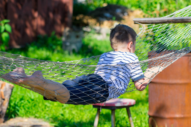 Веселий хлопчик лежить на гамаку в саду
. - Фото, зображення