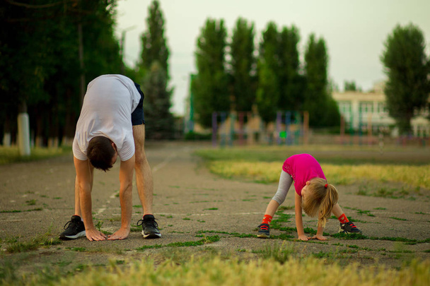 Atletik genç baba ve küçük kızı stadyumda egzersizleri yapın. Sağlıklı yaşam tarzı - Fotoğraf, Görsel