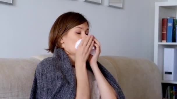 Woman sitting on a sofa, feeling ill and sneezing - Video, Çekim