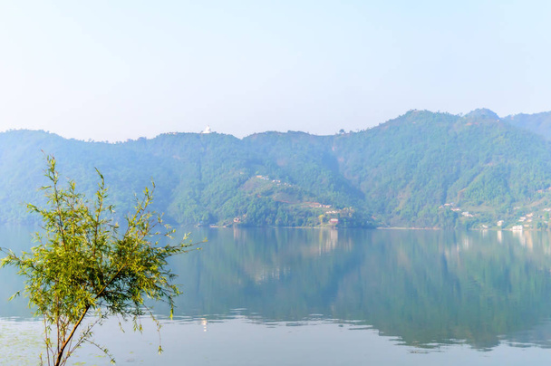 Fotografía de otoño colorido lago de montaña con cielo despejado. Paisaje de gran angular del lago Pokhara en Katmandú Nepal. Mirada de película vintage. Libertad de vacaciones, concepto de simplicidad
. - Foto, imagen