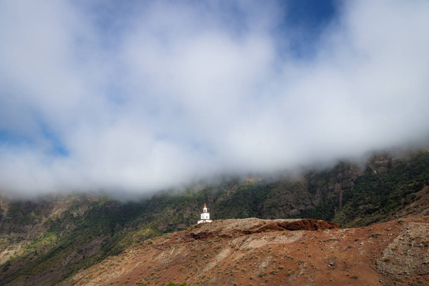 La iglesia La Candelaria en una colina roja con montaña verde y gran nube, Frontera, El Golfo, El Hierro, Islas Canarias, España
 - Foto, Imagen