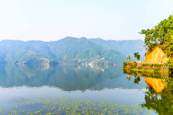 Photographie de lac coloré d'automne, montagne, ciel clair avec reflexation dans l'eau. Paysage grand angle du lac Pokhara à Katmandou Népal. Un look film vintage. Vacances Liberté, Simplicité Concept
. - Photo, image