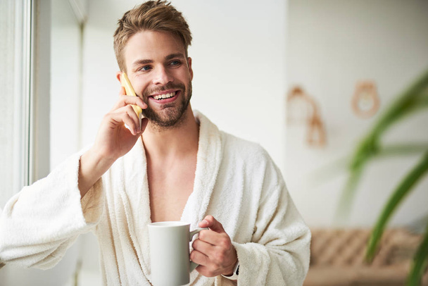 Delighted young man talking on phone in morning - Φωτογραφία, εικόνα